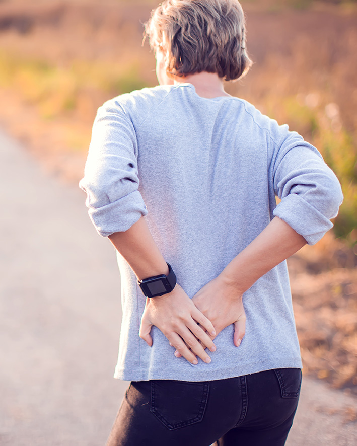 Woman holding back in pain, experiencing the physical symptoms of grief