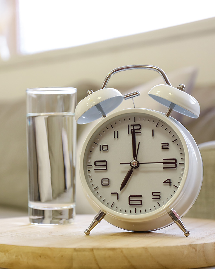 Alarm clock and glass of water for someone experiencing trauma symptoms and in need of therapy in NY or NJ